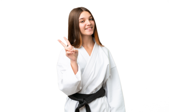 Teenager girl doing karate over isolated chroma key background smiling and showing victory sign