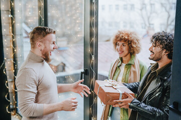 Fototapeta premium Man welcoming guests on holiday with gifts near door at home