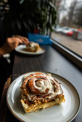 Close-up amateur photo of cinnamon rolls on a clear, soft background, highlighting their delicious, gooey texture. Pistachio and different toppings. Cinnamon roll in a plate. People eating.
