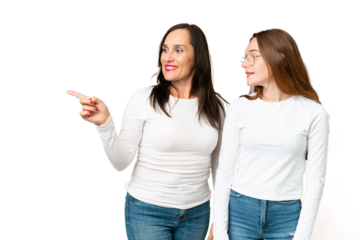 mother and daughter over isolated chroma key background pointing to the side to present a product