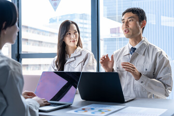 会議をする作業着を着た男女
