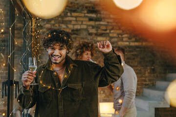 A group of friends dancing with raising glasses of champagne on the Happy New Year party