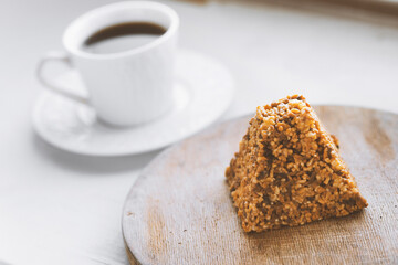 Cup of coffee and a piece of cake on a wooden board