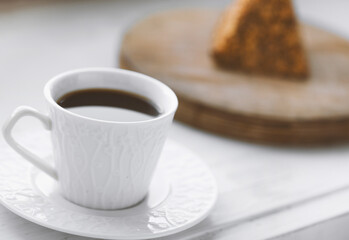 Cup of coffee and a piece of cake on a wooden board