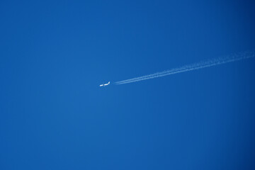 Airplane in the blue sky with white trace of the plane.