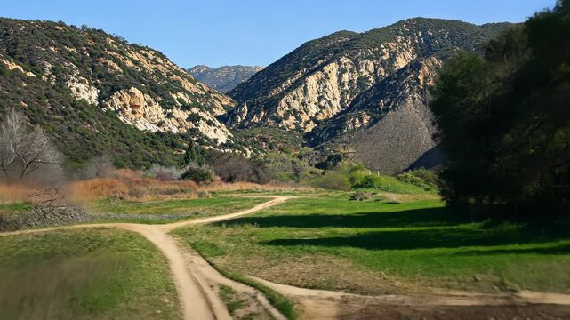 A dirt path splits in two, leading towards the mountain range in the distance