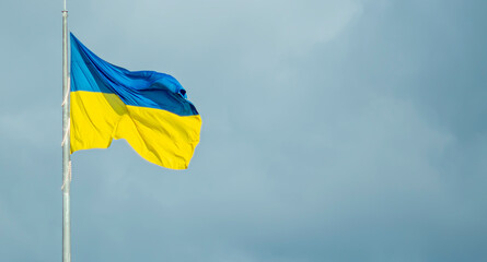 
The flag of Ukraine against the background of a dark sky in windy weather.