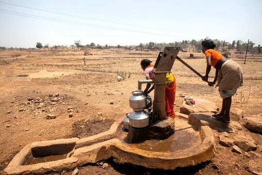 Tribal woman pumping water from hand pump, India