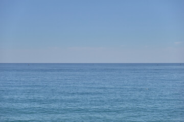 Obraz premium A vast expanse of calm blue ocean meets a clear blue sky on the horizon. The water is still and serene, creating a peaceful and tranquil atmosphere