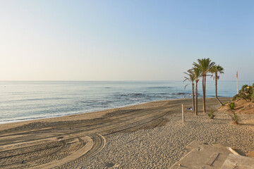 View of Santa Ana beach at Cape Bil Bil, Benalmadena, Malaga, empty, with sand, palm trees and the horizon on the Mediterranean Sea