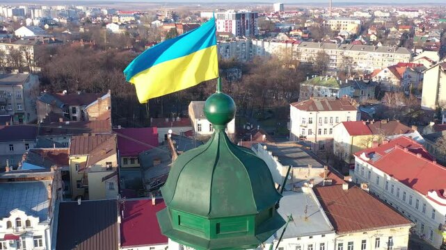 A quadcopter captures a stunning panorama of Drohobych, Ukraine, focusing on the central square where a historic town hall stands proudly. The video highlights the town's charm and rich heritage from