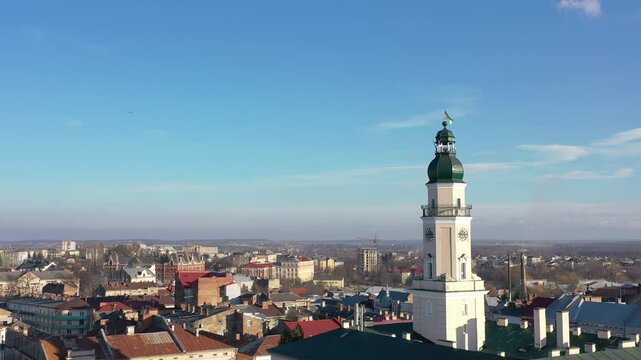 A quadcopter captures a stunning panorama of Drohobych, Ukraine, focusing on the central square where a historic town hall stands proudly. The video highlights the town's charm and rich heritage from