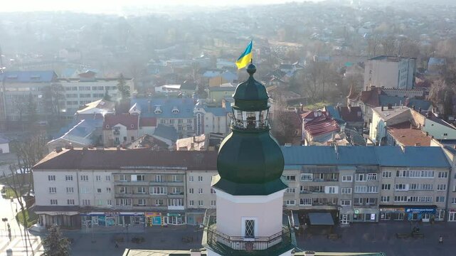 A quadcopter captures a stunning panorama of Drohobych, Ukraine, focusing on the central square where a historic town hall stands proudly. The video highlights the town's charm and rich heritage from
