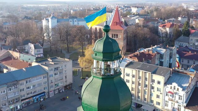 A quadcopter captures a stunning panorama of Drohobych, Ukraine, focusing on the central square where a historic town hall stands proudly. The video highlights the town's charm and rich heritage from