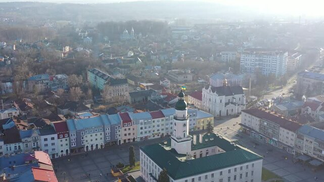 A quadcopter captures a stunning panorama of Drohobych, Ukraine, focusing on the central square where a historic town hall stands proudly. The video highlights the town's charm and rich heritage from