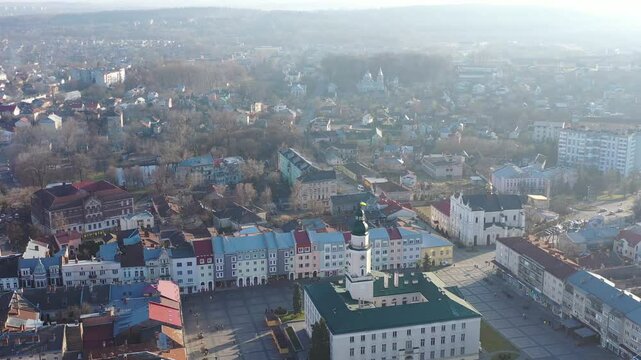 A quadcopter captures a stunning panorama of Drohobych, Ukraine, focusing on the central square where a historic town hall stands proudly. The video highlights the town's charm and rich heritage from