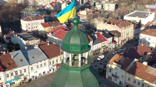 A quadcopter captures a stunning panorama of Drohobych, Ukraine, focusing on the central square where a historic town hall stands proudly. The video highlights the town's charm and rich heritage from