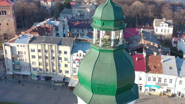 A quadcopter captures a stunning panorama of Drohobych, Ukraine, focusing on the central square where a historic town hall stands proudly. The video highlights the town's charm and rich heritage from