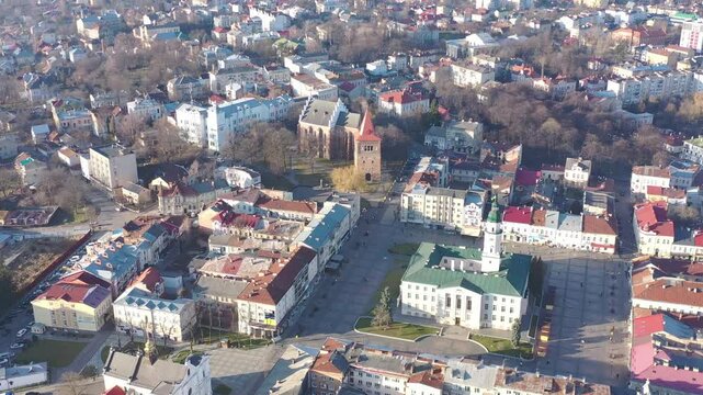 A quadcopter captures a stunning panorama of Drohobych, Ukraine, focusing on the central square where a historic town hall stands proudly. The video highlights the town's charm and rich heritage from