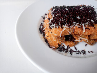 Pisang Bakar Coklat Keju or Grilled Banana Chocolate Cheese serve with chocolate sprinkles and cheddar cheese graters on white plate.