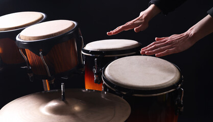 Drummer playing drums, different percussive musical instruments on a black background