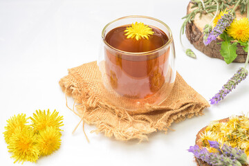 glass of dandelion and lavender infusion with aromatic flowers on white background