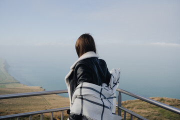 the girl looks at the sea from the cliff