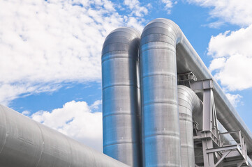 The photo shows pipeline lines against the backdrop of blue sky and clouds