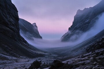 Fototapeta premium Mist drifts through a majestic mountain valley at twilight, creating a mystical and ethereal landscape of peaks embracing the encroaching fog.