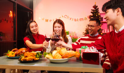 Lively New Year Eve and christmas party Asian friends and colleagues of various ages celebrating together. Champagne, wine, gift boxes, festive decorations create a warm, joyful holiday atmosphere.