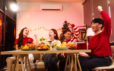 Lively New Year Eve and christmas party Asian friends and colleagues of various ages celebrating together. Champagne, wine, gift boxes, festive decorations create a warm, joyful holiday atmosphere.