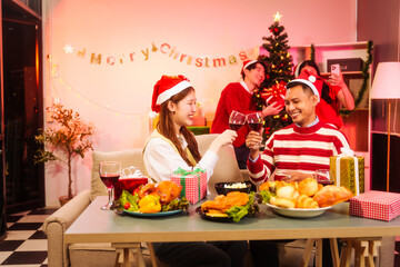 Lively New Year Eve and christmas party Asian friends and colleagues of various ages celebrating together. Champagne, wine, gift boxes, festive decorations create a warm, joyful holiday atmosphere.