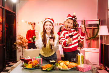 Lively New Year Eve and christmas party Asian friends and colleagues of various ages celebrating together. Champagne, wine, gift boxes, festive decorations create a warm, joyful holiday atmosphere.