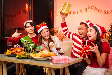 Lively New Year Eve and christmas party Asian friends and colleagues of various ages celebrating together. Champagne, wine, gift boxes, festive decorations create a warm, joyful holiday atmosphere.