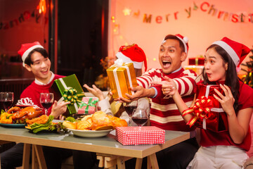 Lively New Year Eve and christmas party Asian friends and colleagues of various ages celebrating together. Champagne, wine, gift boxes, festive decorations create a warm, joyful holiday atmosphere.