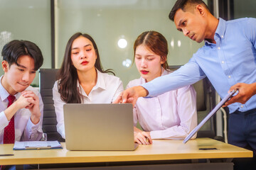 Fototapeta premium Two men and two women, including boss and employees, discuss recent mistake. Expressions of disappointment and constructive criticism create a tense, reflective atmosphere around laptops and desks.