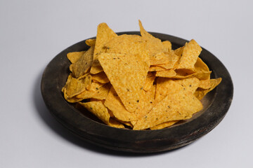 The chips have a triangular shape with a rough texture and small black seasoning specks visible on the surface. They appear crispy and ready to eat, with some chips overlapping each other. 