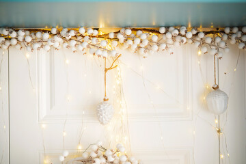Decorative winter lights and ornaments on a white door with cotton accents
