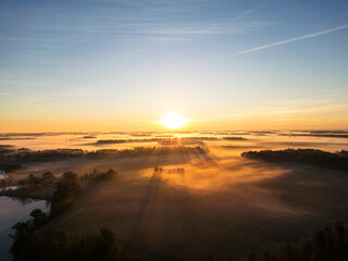 morning sun rising over the horizon casting light and shadows across the landscape with a sleepy farm centered in the golden hour color