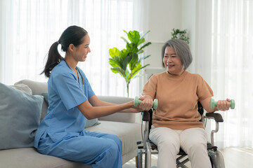 Compassionate caregiver assists elderly woman with home workout using dumbbells, promoting health, happiness, and wellness in retirement. Supportive senior care and exercise.
