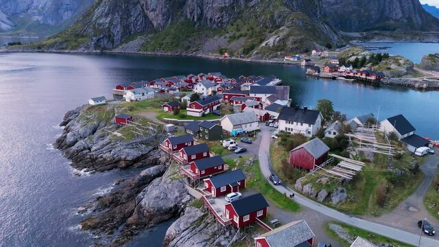 Hamnoy, Norway, aerial footage, drone shots, red huts near the sea with big mountain in the background, calm fishing village near the ocean