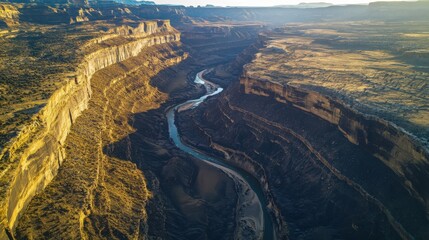 Aerial view of a vast canyon carved by a winding river under the warm glow of sunset in a rugged landscape