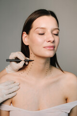 Cosmetologist is drawing dotes before botulinum toxin injection in platysma of a woman. Mark up...
