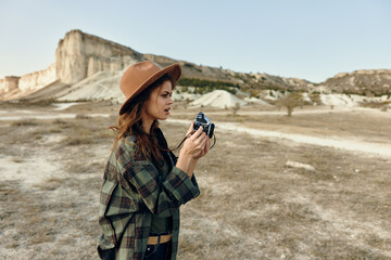 vintage vibes woman in plaid shirt and hat captures the desert with old camera