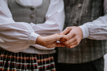 Close-up of a couple holding hands, wearing traditional clothing. A gentle, intimate moment showcasing connection and affection.