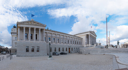 house of parliament building with colonnade in Vienna and two flags above