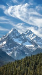 Fototapeta premium Majestic snow-capped mountains rise above lush forests under a vibrant blue sky, capturing the beauty of nature's untouched wilderness