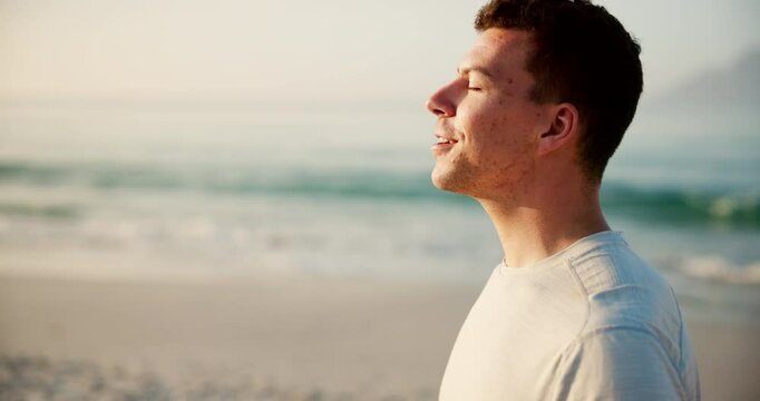 Happy man, relax and breathing with fitness on beach for peace, health and wellness by sea in nature. Young, male person or athlete with smile for fresh air, breeze or calm environment on ocean coast