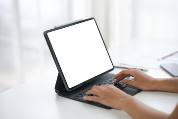Person typing on a tablet with a keyboard attachment, modern technology setup for work or online activities in a well-lit environment.