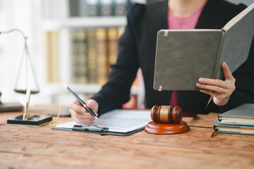 A lawyer working in a law office, reviewing documents and making notes, with a gavel and scales of justice on the desk.